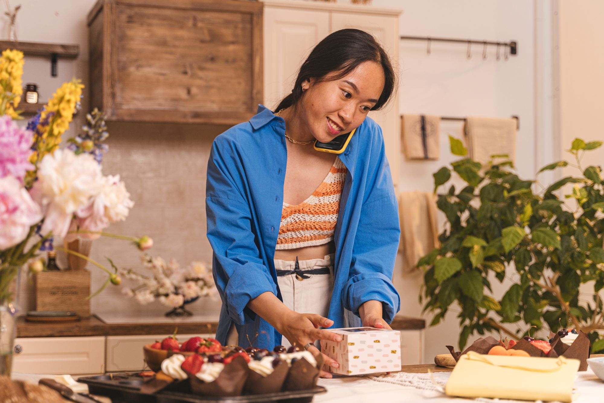 A bakery owner boxing pastries while taking a phone call