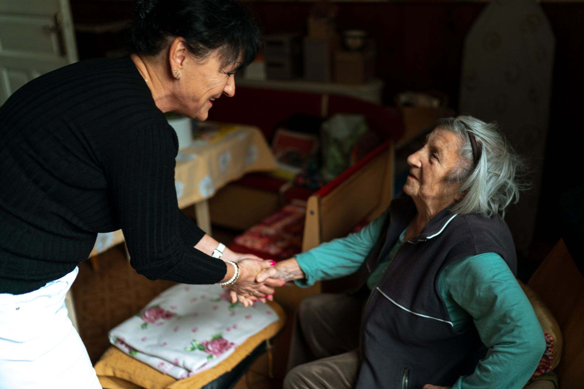 A caregiver greeting an older woman at home