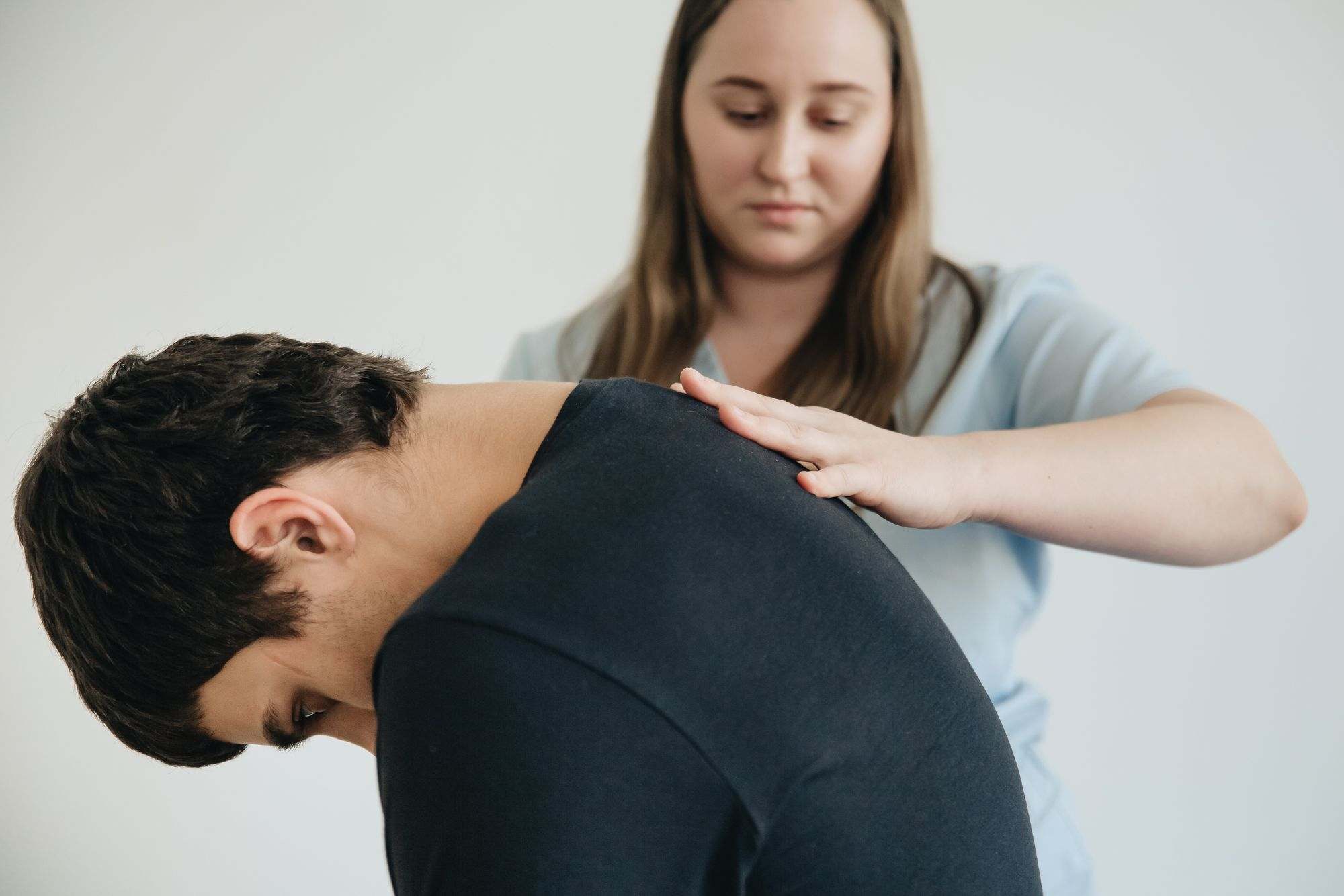 A practitioner checking a patient's upper back in a treatment room
