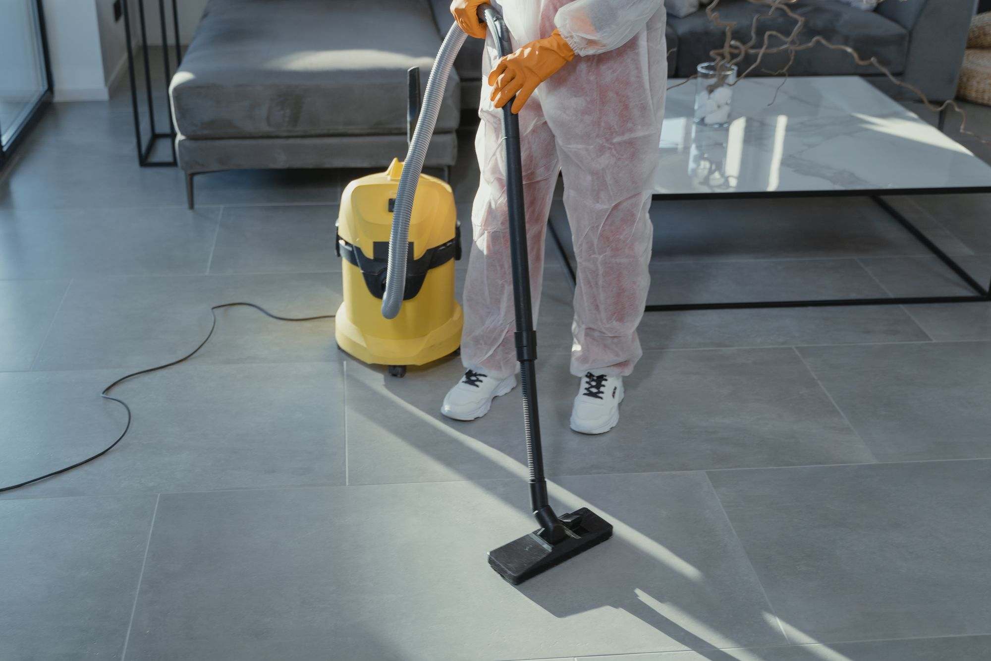 A cleaner vacuuming the floor of a modern living room