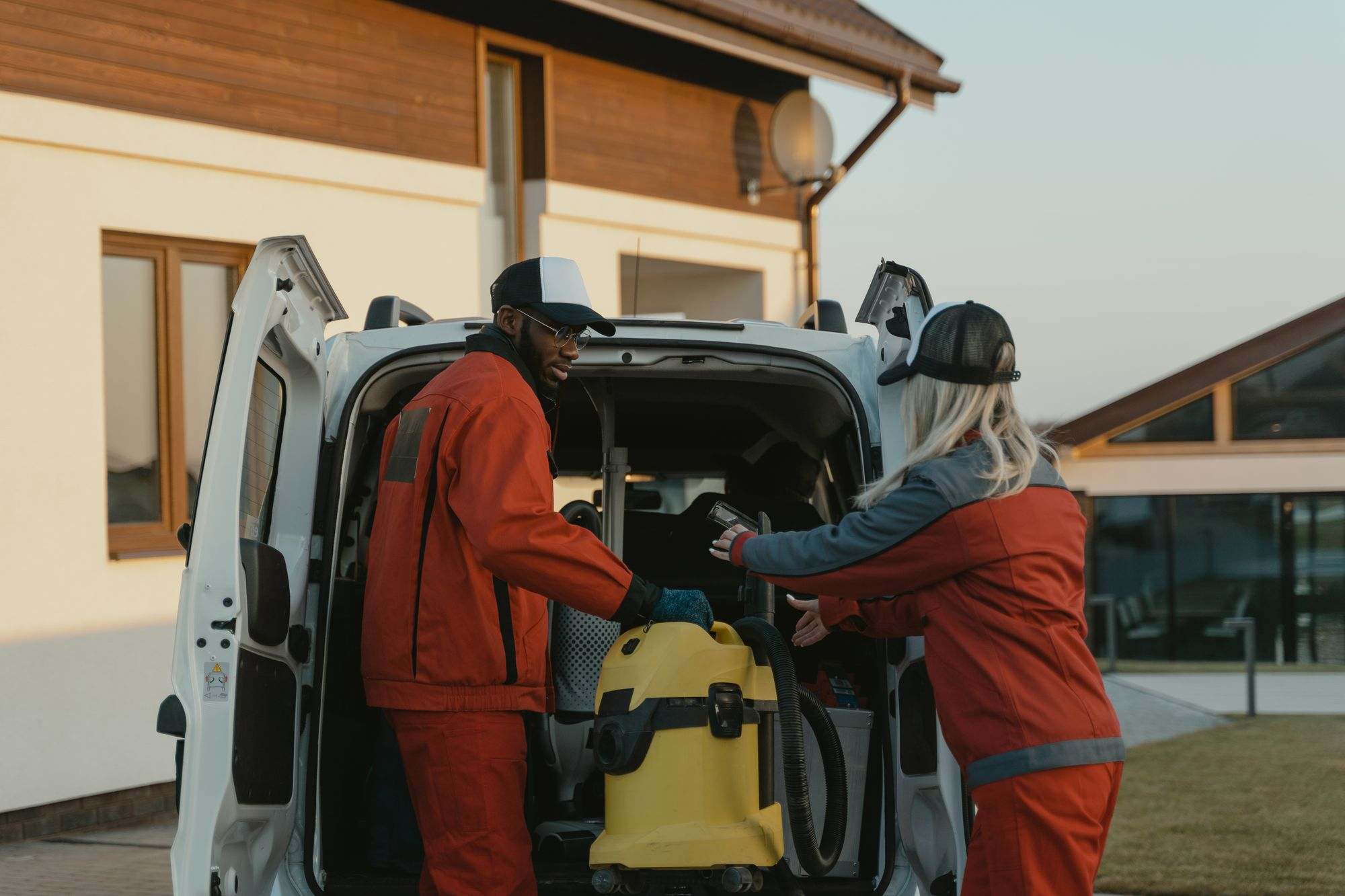 Two cleaners loading equipment into a van