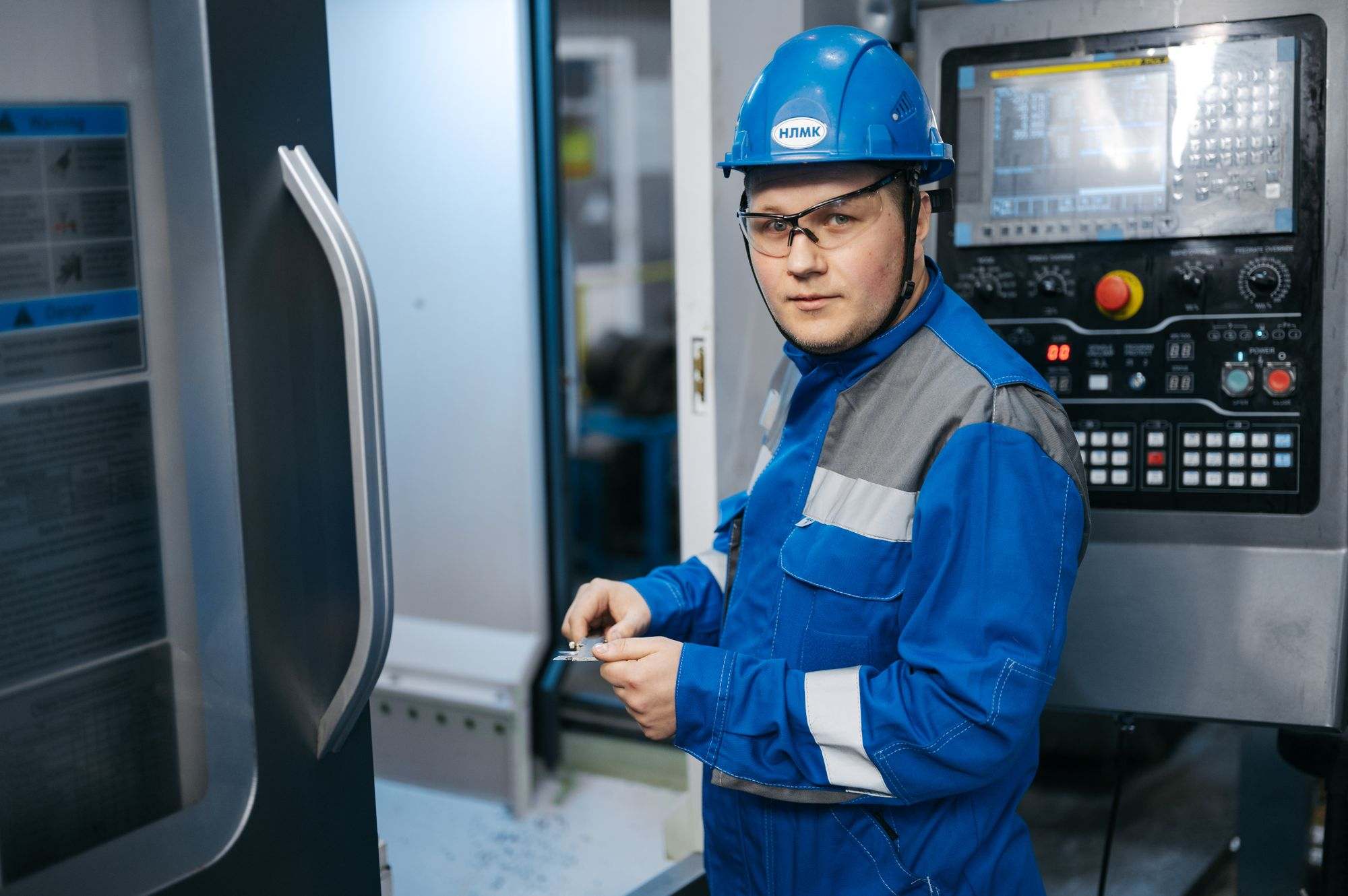 A machinist in safety gear at a CNC machine
