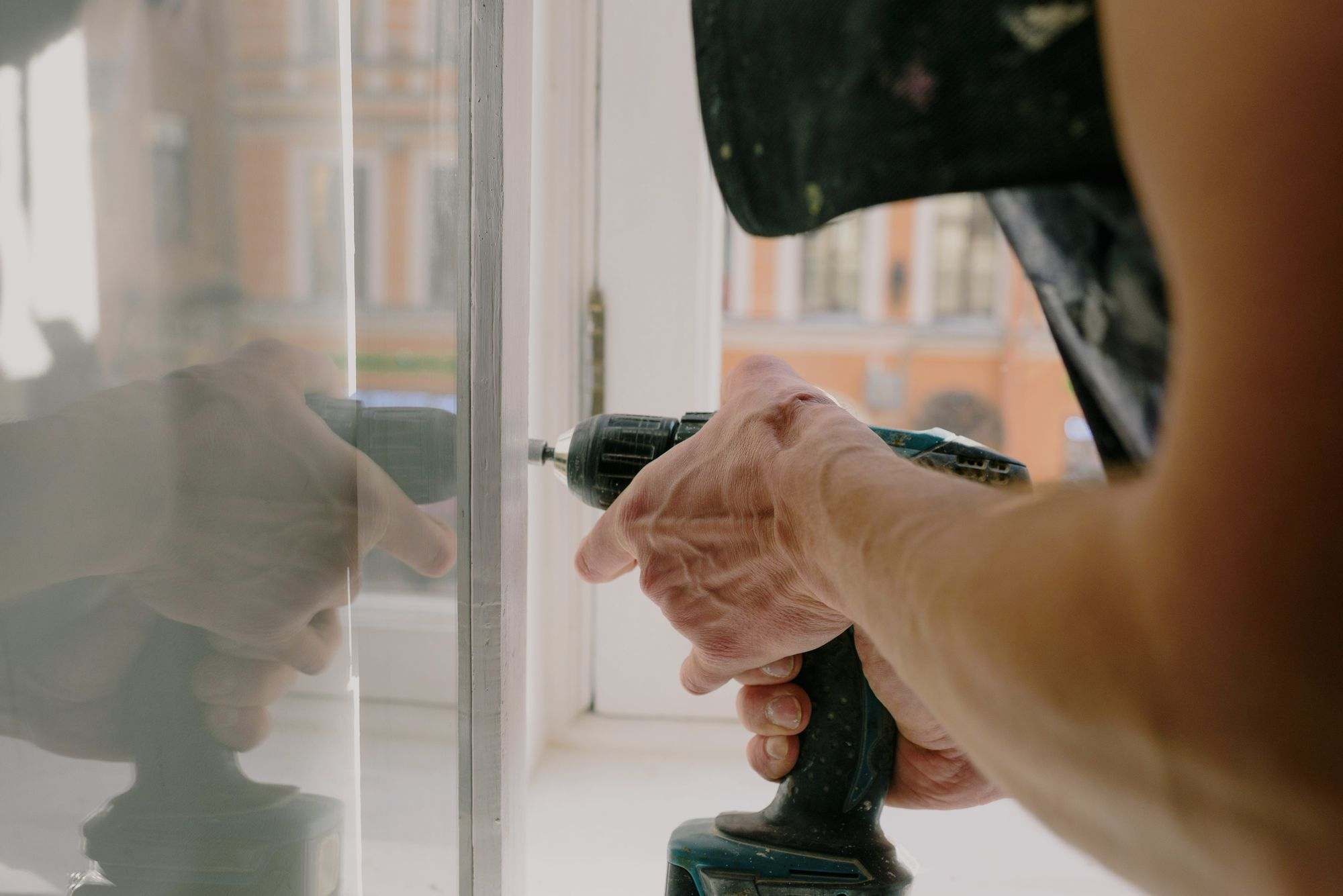 A contractor fixing a window frame with a cordless screwdriver