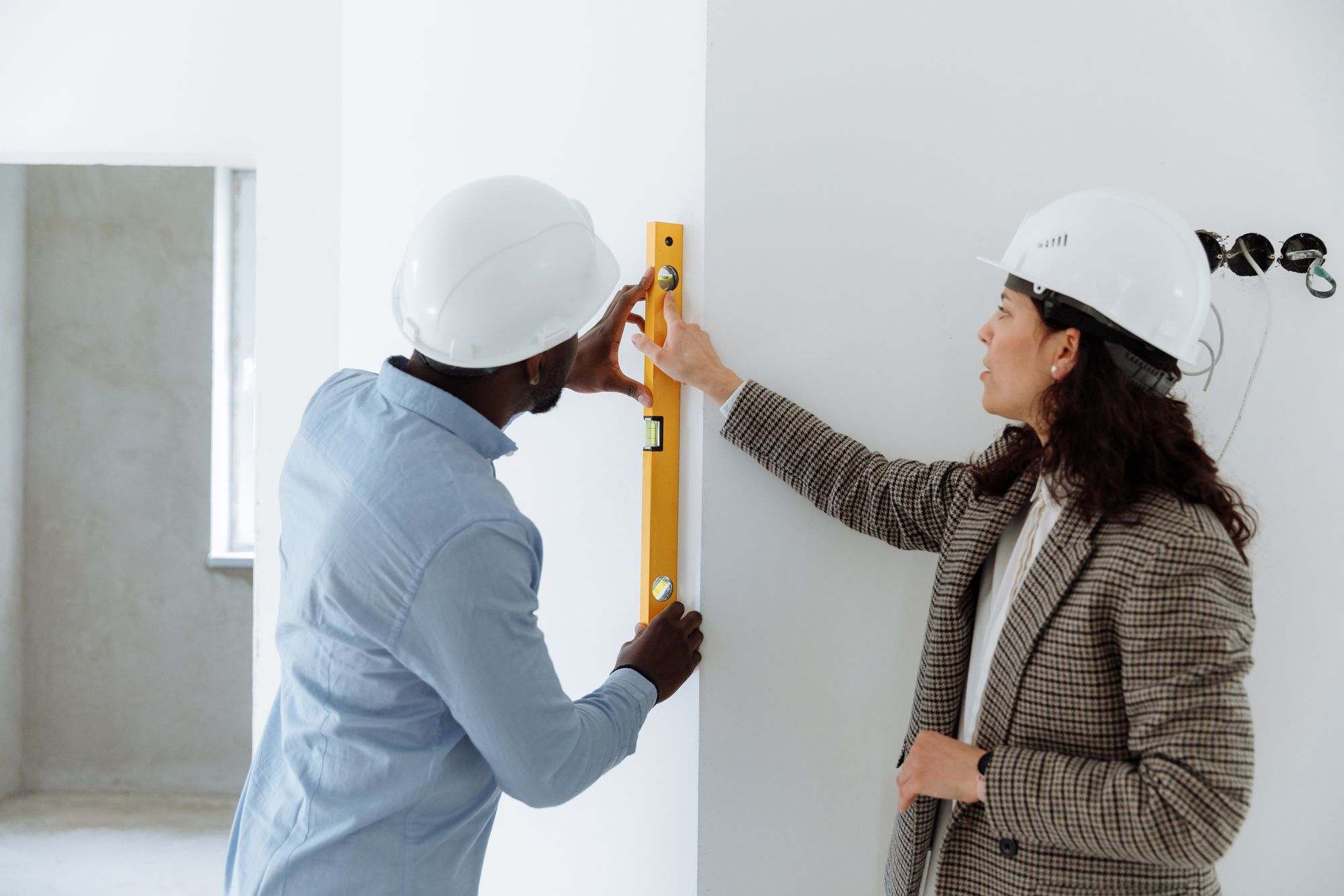 Two contractors checking a wall with a spirit level