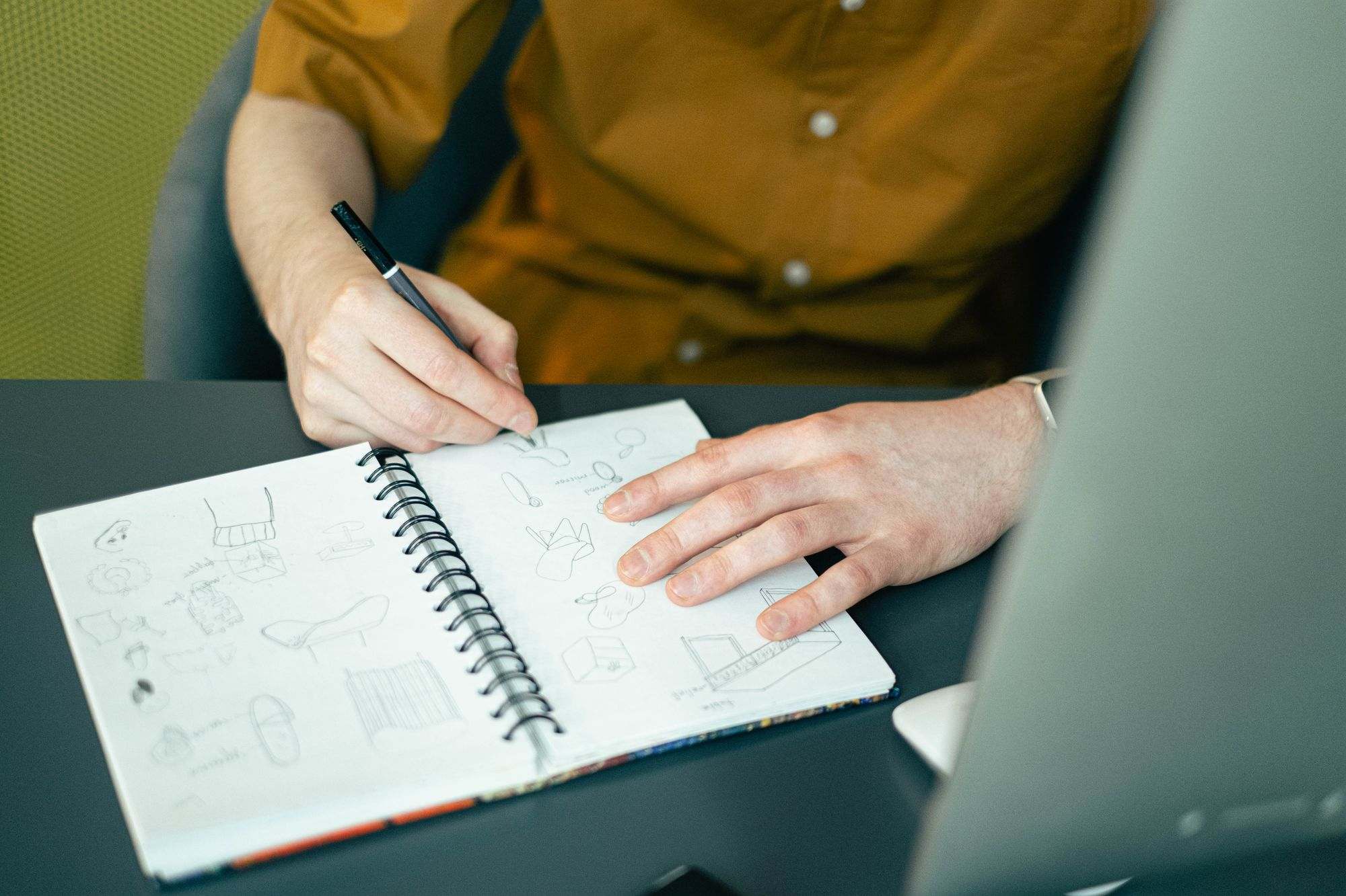 A designer sketching page layouts in a notebook