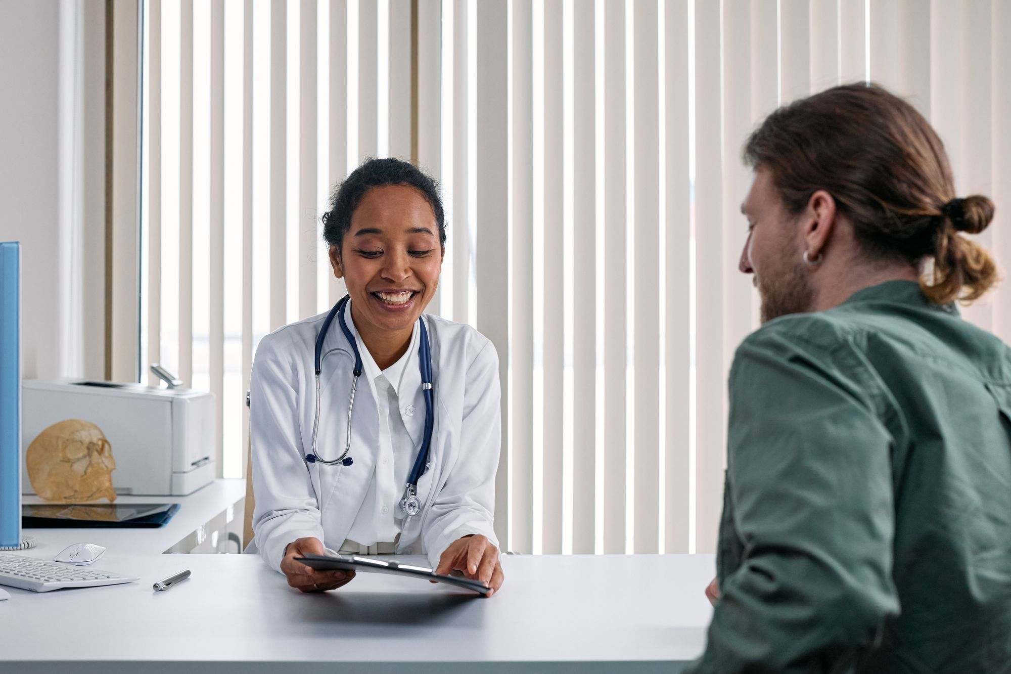 A smiling doctor talking with a patient at a clinic desk