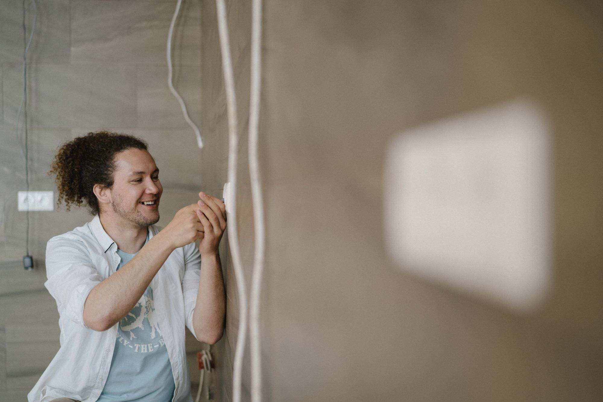 A smiling electrician fitting an outlet on a wall