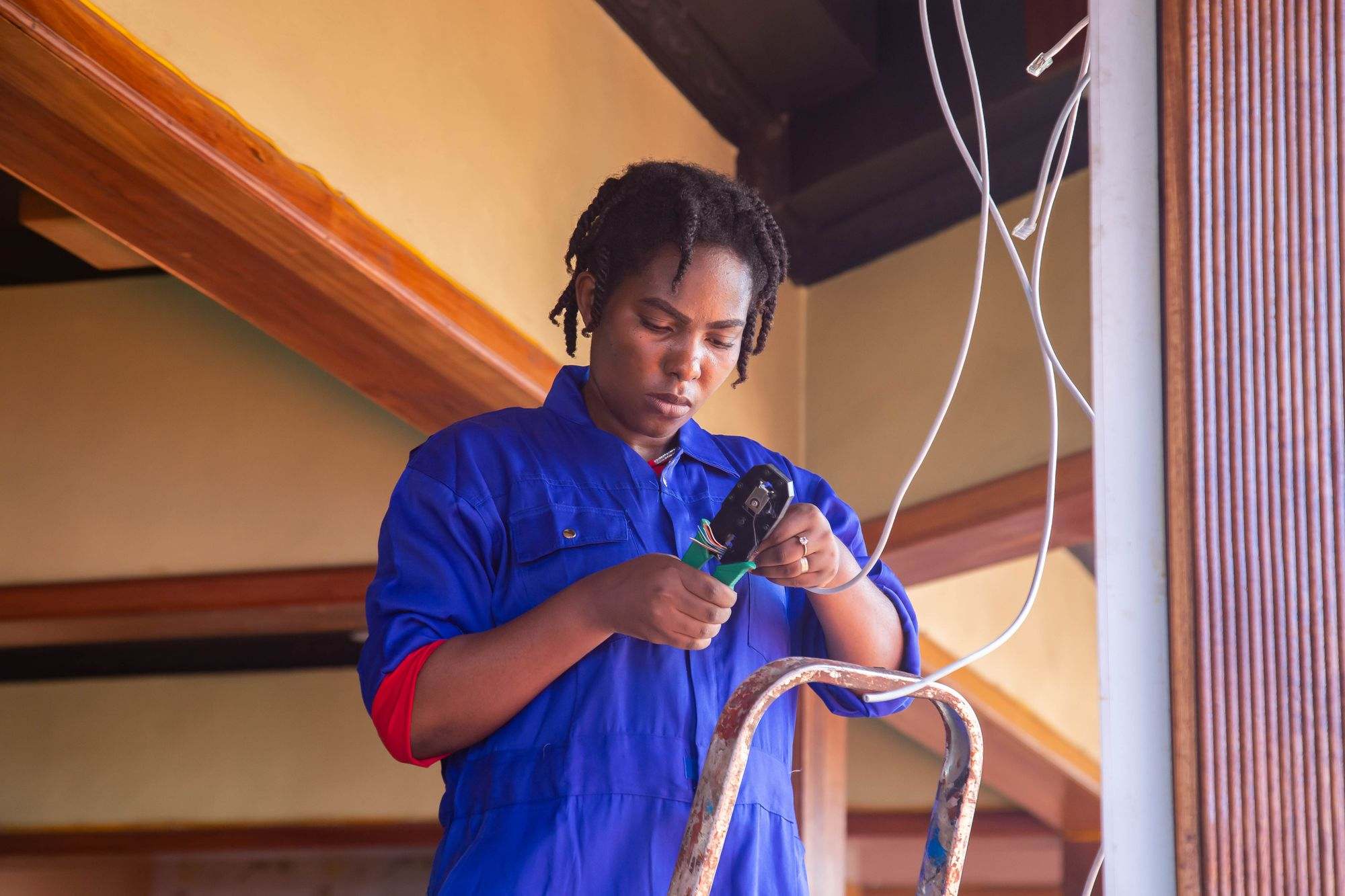 An electrician on a ladder holding cables