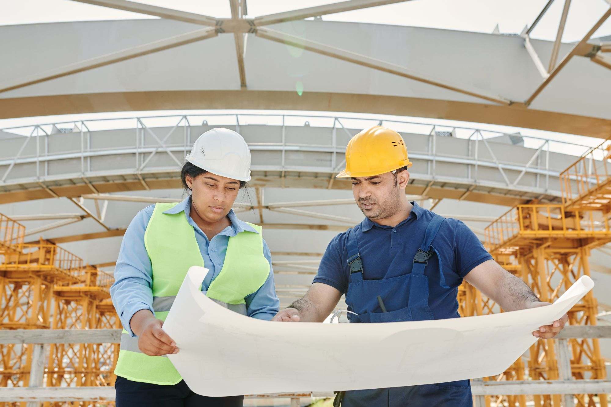 Two builders in hard hats reviewing plans on site