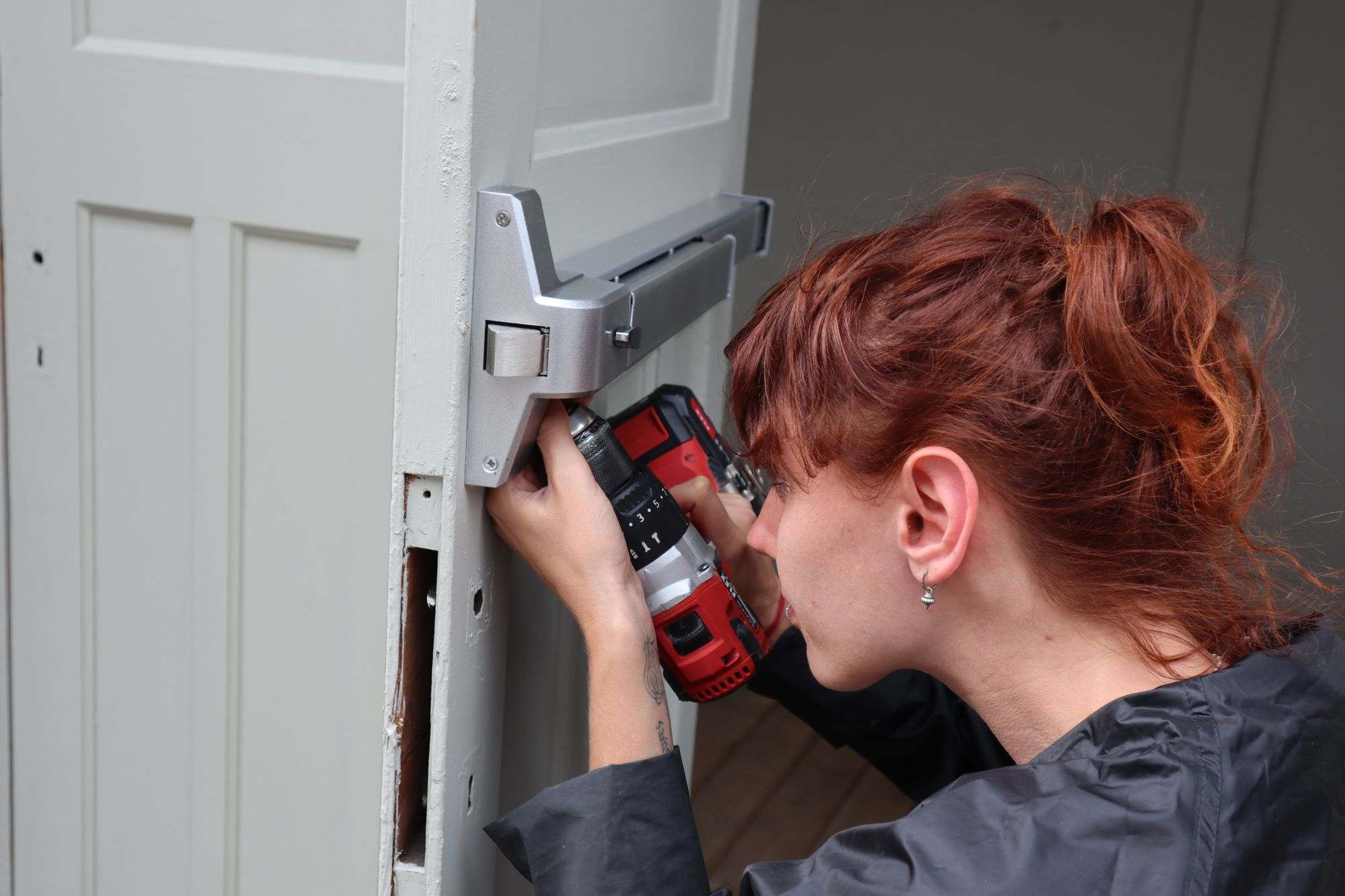 A tradesperson fitting hardware to a door with a drill
