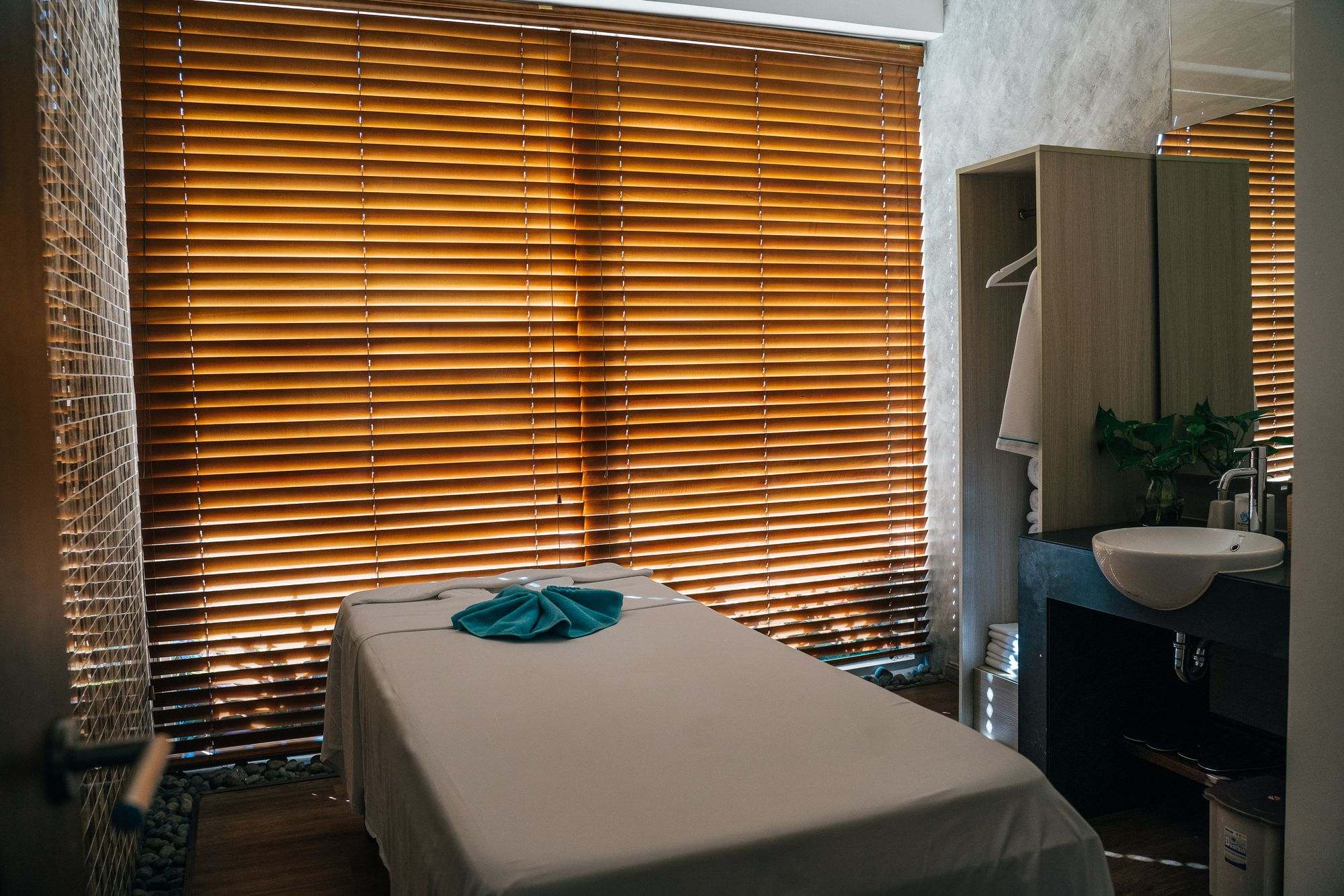 A quiet treatment room with a made-up bed and soft window light