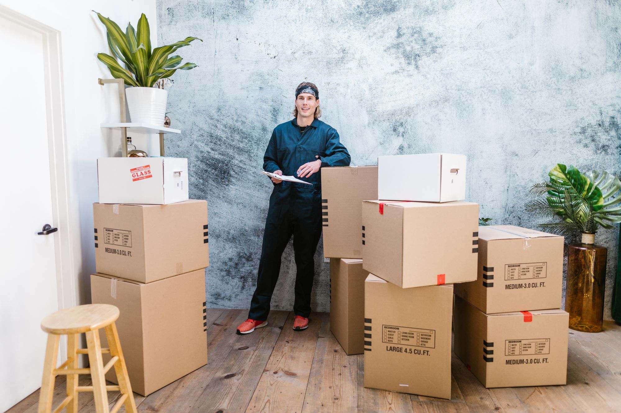 A mover with a clipboard standing beside packed boxes