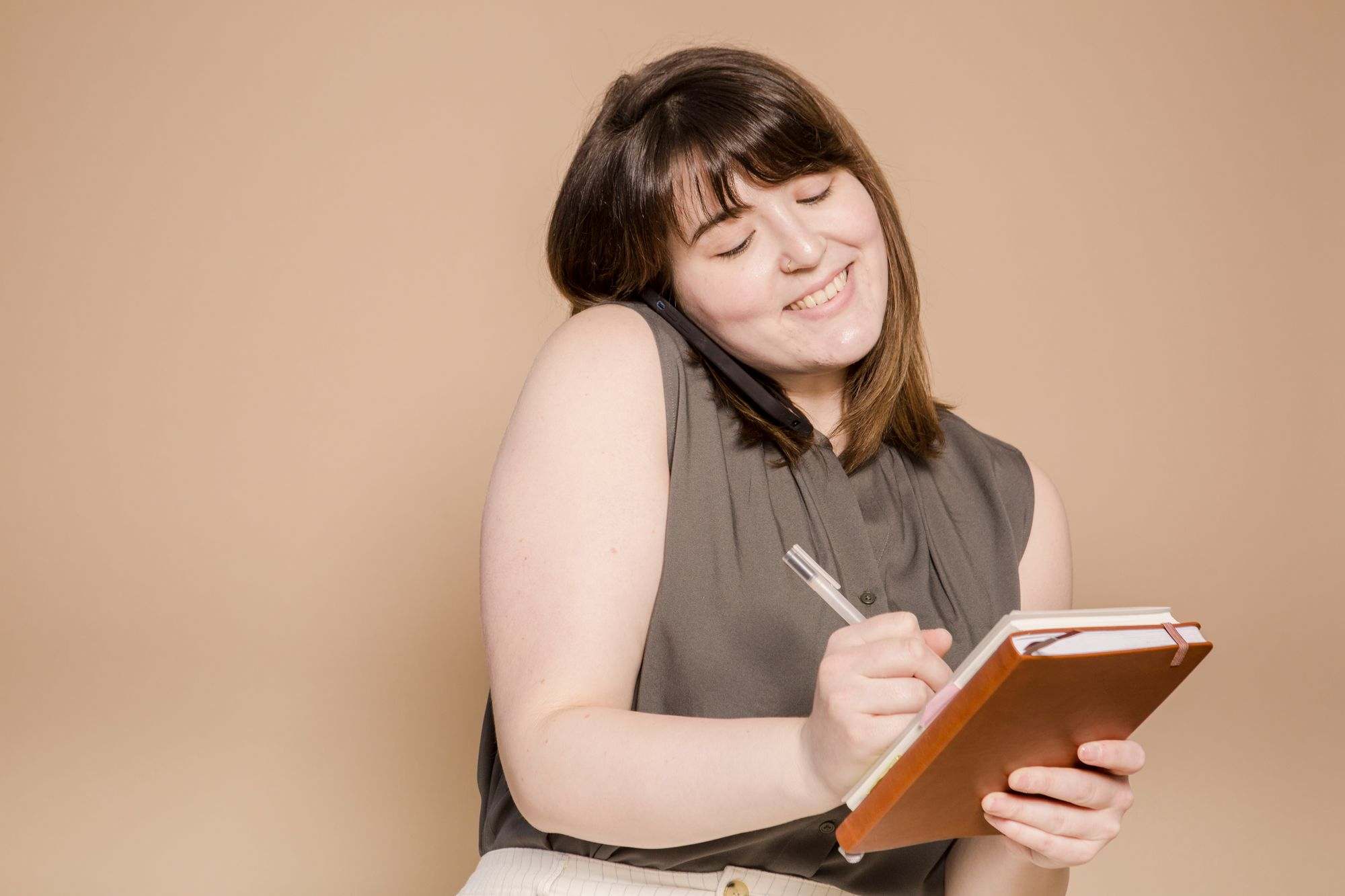A business owner writing in a notebook during a phone call