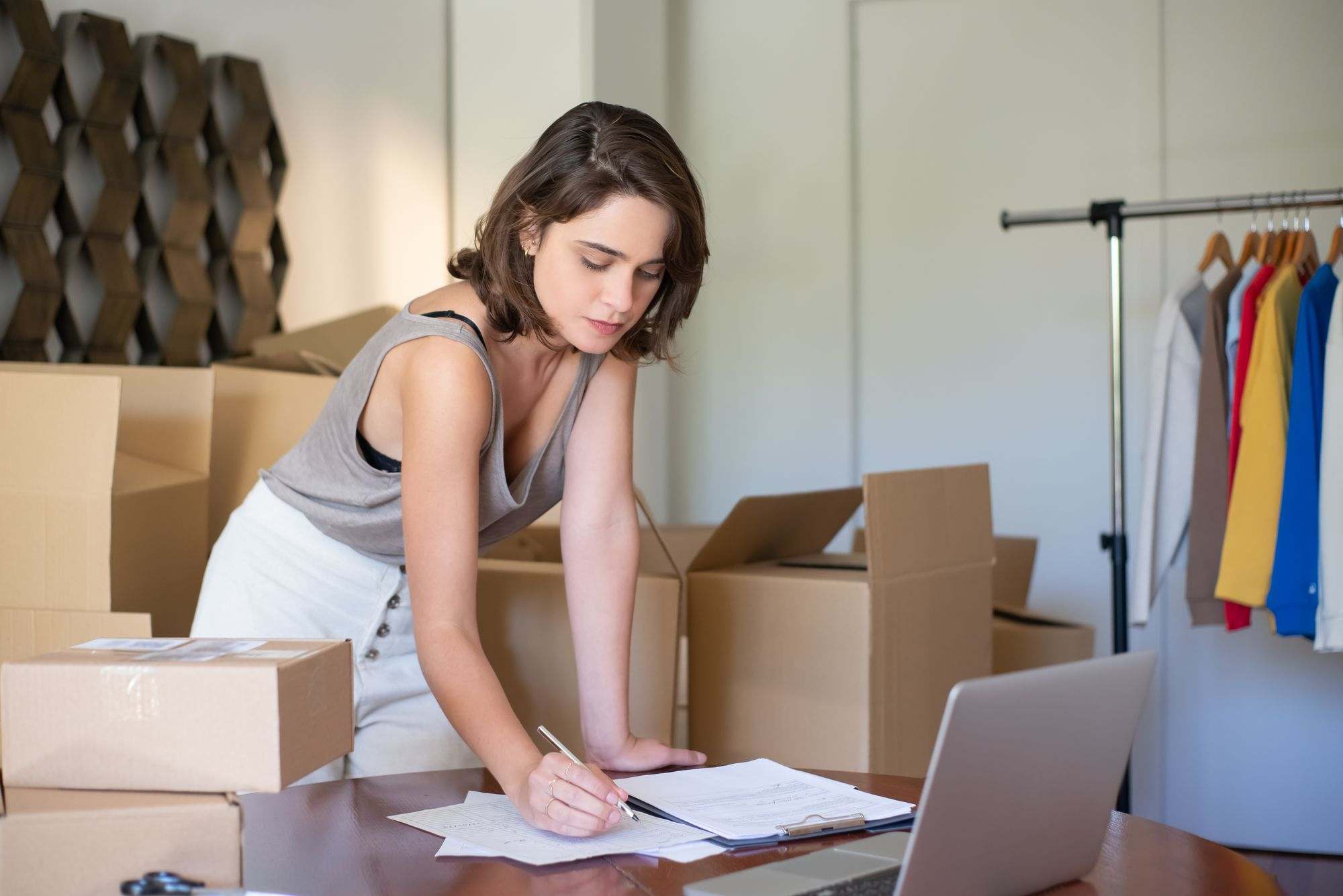 An online shop owner writing notes among shipping boxes