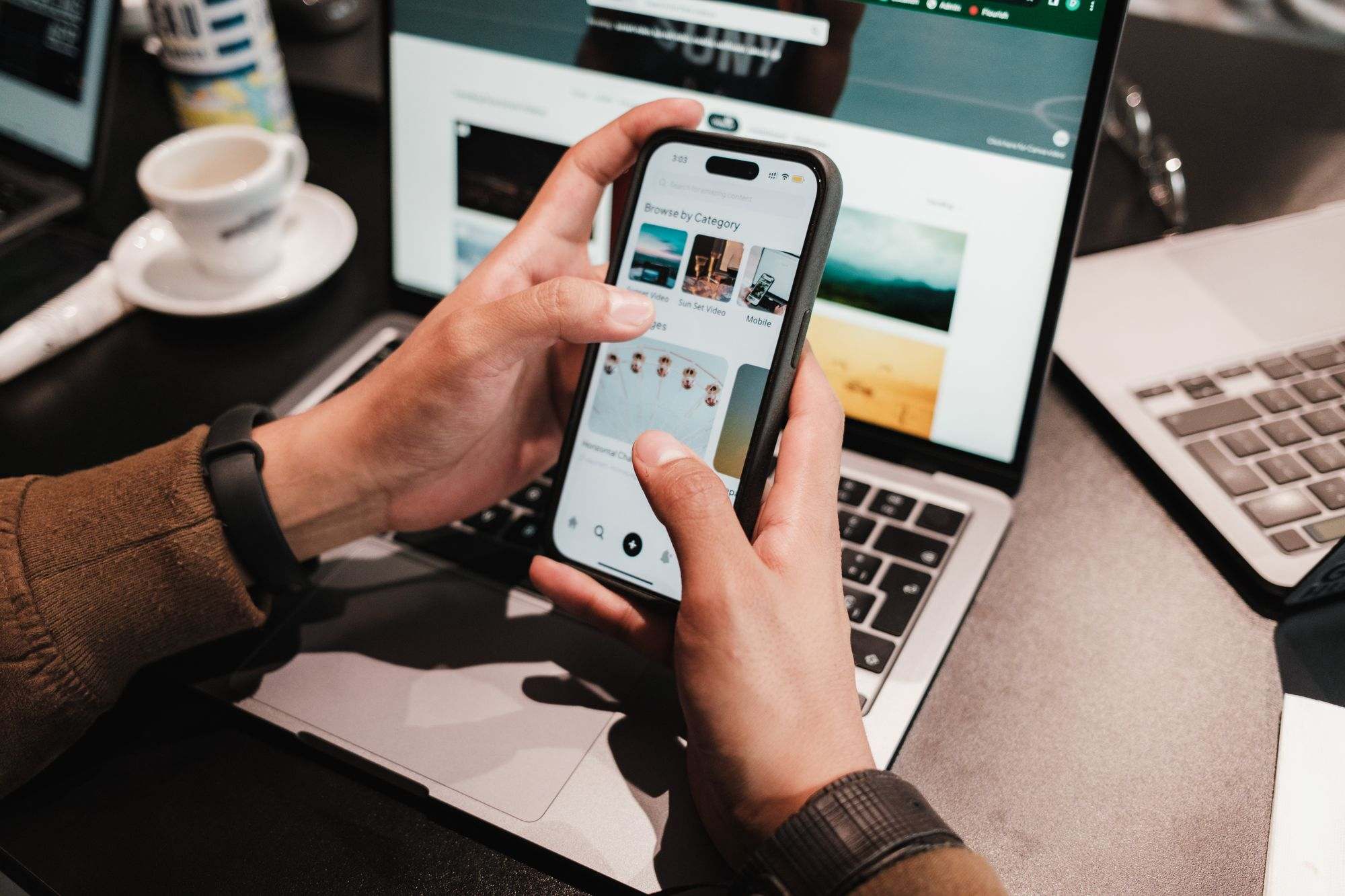 Hands holding a smartphone above a laptop keyboard
