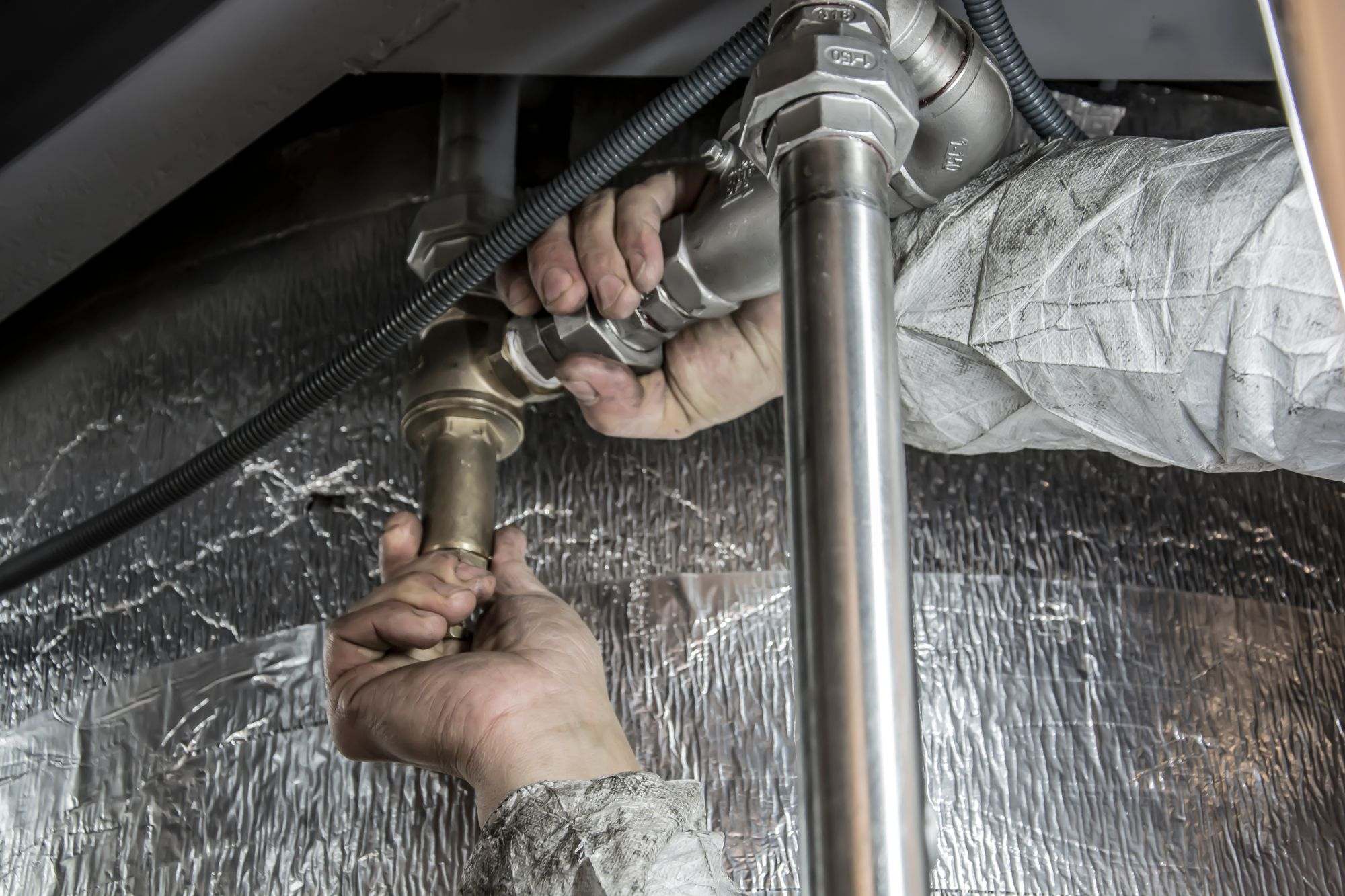 A plumber fitting pipes under a sink