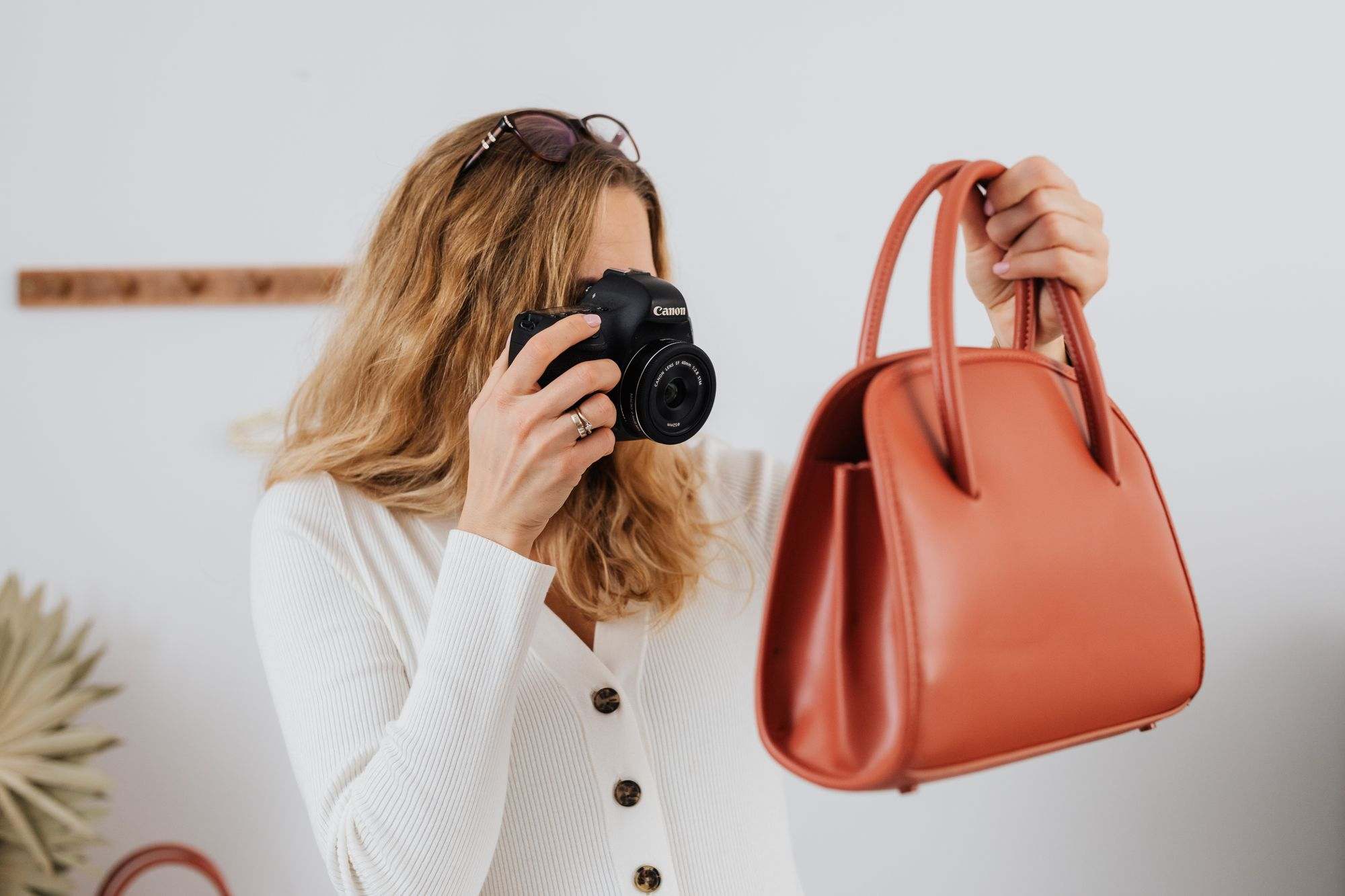 A woman photographing a handbag for an online store