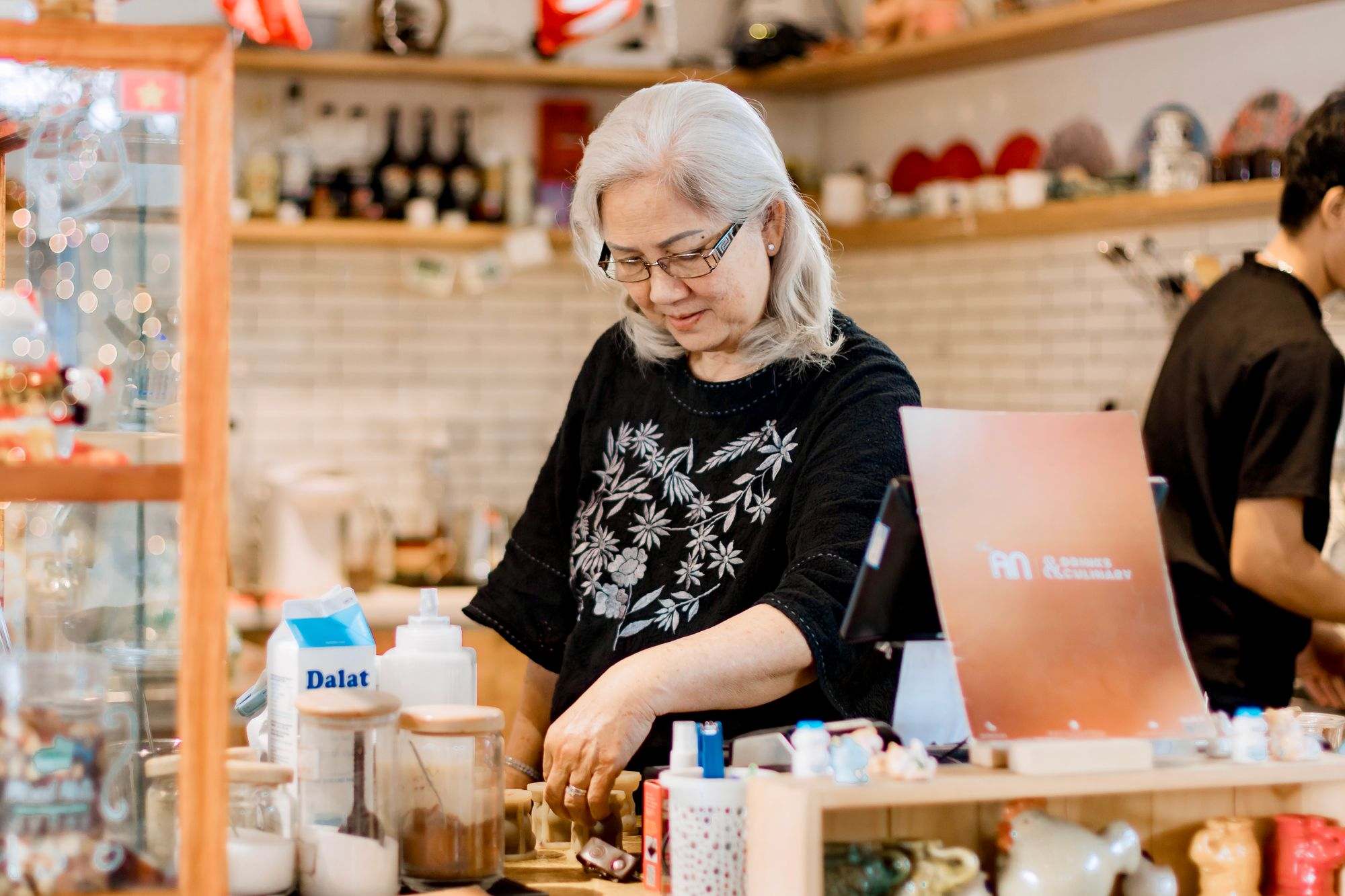 A shop owner working behind the counter of a small shop